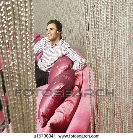 High angle view of a young man wearing hands free device and sitting behind beaded curtain View Large Photo Image Stock Image - High angle view of a young man wearing hands free device and sitting behind beaded curtain. Fotosearch