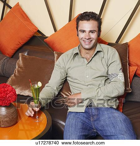Stock Image - Portrait of a young man holding a glass and smiling. Fotosearch