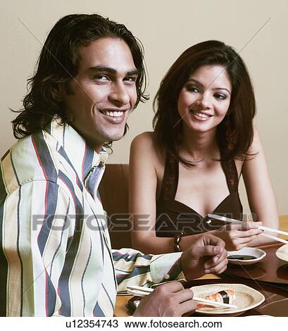 Portrait of a young man sitting with a young woman at a dining table and smiling View Large Photo Image Stock Image - Portrait of a young man sitting with a young woman at a dining table and smiling. Fotosearch