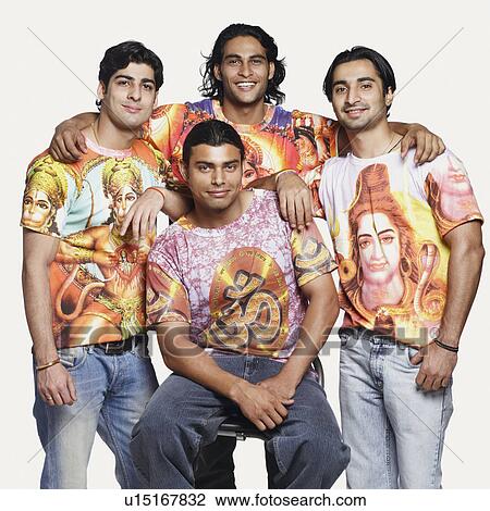 Stock Image - Portrait of a young man sitting with his friends standing behind him and smiling. Fotosearch