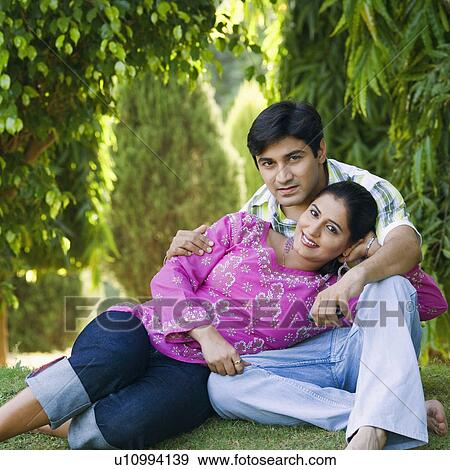 Stock Photo - Portrait of a young woman reclining on a young man's lap in a lawn. Fotosearch