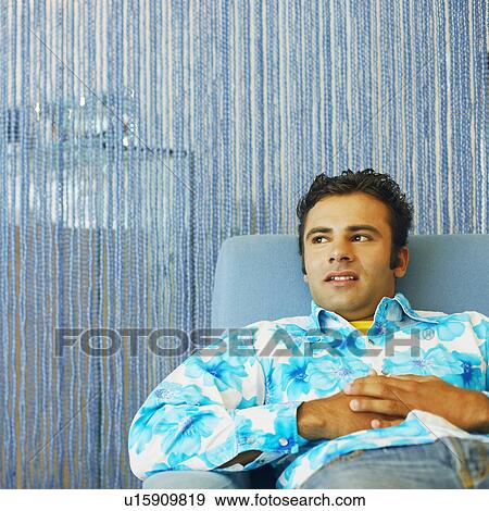 Young man reclining in an armchair View Large Photo Image Stock Photo - Young man reclining in an armchair. Fotosearch