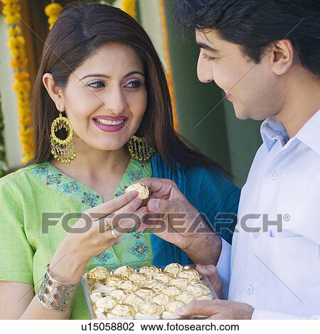 Young woman giving a cookie to a young man View Large Photo Image Stock Image - Young woman giving a cookie to a young man. Fotosearch