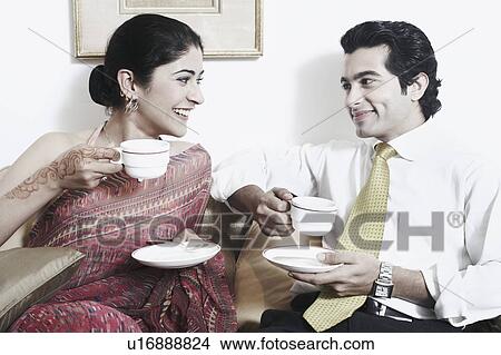 Picture - Close-up of a young couple holding cups of tea. Fotosearch