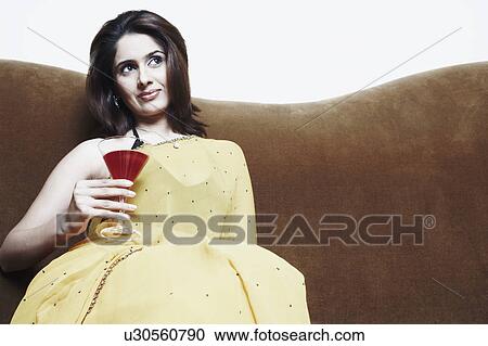 Stock Image - Close-up of a young woman holding a martini glass. Fotosearch