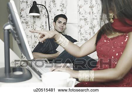 Stock Image - Close-up of a young woman pointing towards a computer monitor. Fotosearch