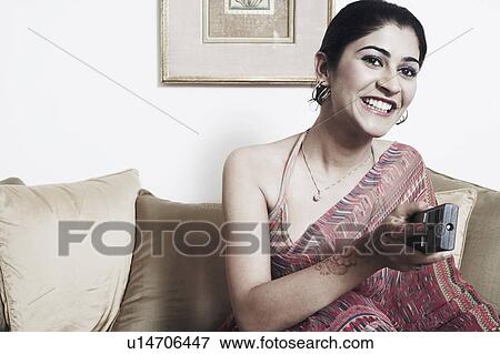 Stock Photo - Close-up of a young woman using a remote control. Fotosearch
