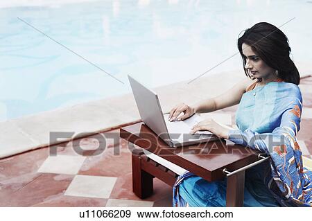 Stock Photo - High angle view of a young woman using a laptop. Fotosearch