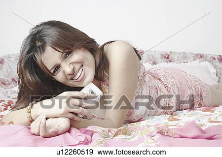 Portrait of a young woman holding a mobile phone View Large Photo Image Stock Photo - Portrait of a young woman holding a mobile phone. Fotosearch
