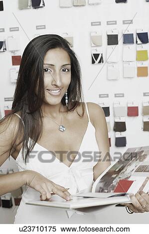Stock Photography - Portrait of a young woman holding a pencil and a magazine. Fotosearch