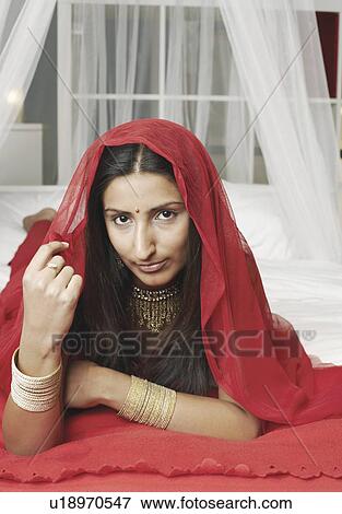 Portrait of a young woman lying on the bed with a stole on her head View Large Photo Image Stock Photo - Portrait of a young woman lying on the bed with a stole on her head. Fotosearch
