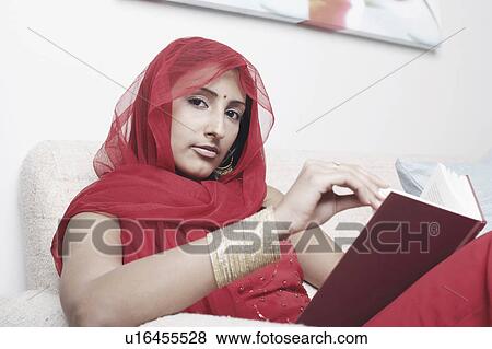 Portrait of a young woman sitting on a couch View Large Photo Image Stock Photo - Portrait of a young woman sitting on a couch. Fotosearch