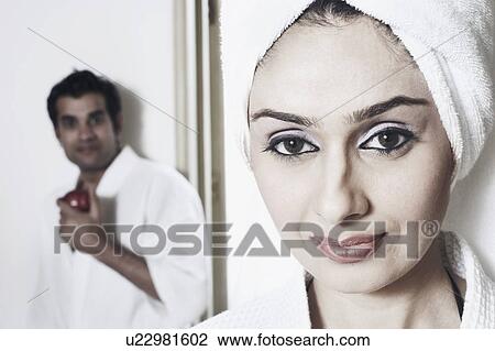 Portrait of a young woman smiling with a young man standing behind her View Large Photo Image Stock Image - Portrait of a young woman smiling with a young man standing behind her. Fotosearch