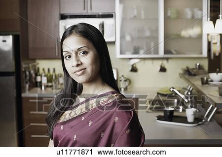 Stock Image - Portrait of a young woman standing in the kitchen. Fotosearch