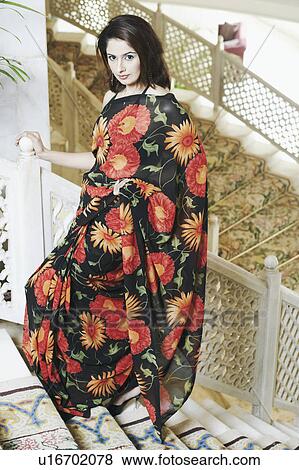 Portrait of a young woman standing on a staircase View Large Photo Image Stock Photo - Portrait of a young woman standing on a staircase. Fotosearch