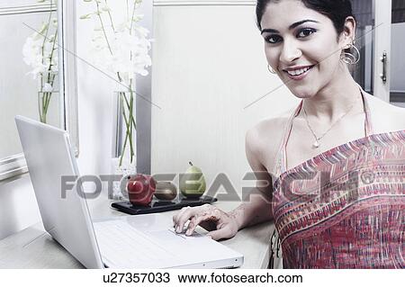 Stock Image - Portrait of a young woman using a laptop. Fotosearch