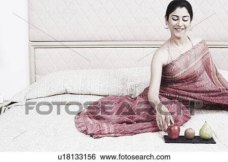 Young woman sitting on the bed View Large Photo Image Stock Photograph - Young woman sitting on the bed. Fotosearch