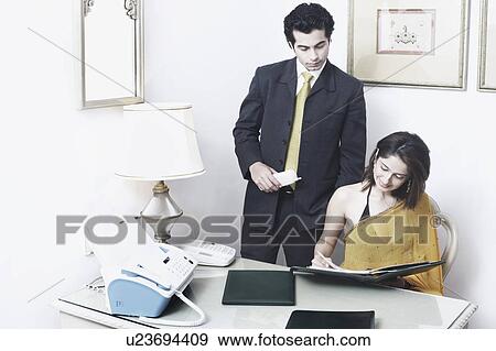 Stock Photo - Businessman and a businesswoman reading documents in an office. Fotosearch