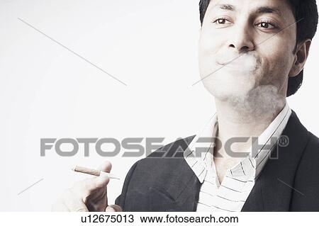 Stock Image - Close-up of a businessman smoking a cigar. Fotosearch