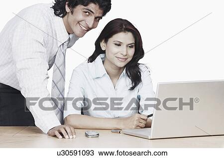 Stock Image - Portrait of a businessman and a businesswoman using a laptop. Fotosearch