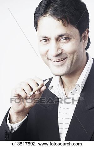 Portrait of a businessman holding a cigar View Large Photo Image Stock Image - Portrait of a businessman holding a cigar. Fotosearch