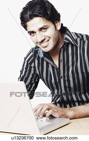 Stock Image - Portrait of a young man using a laptop. Fotosearch