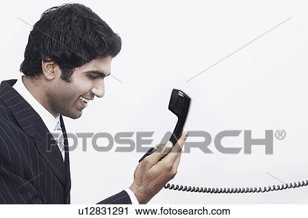 Side profile of a businessman holding a telephone receiver View Large Photo Image Stock Image - Side profile of a businessman holding a telephone receiver. Fotosearch