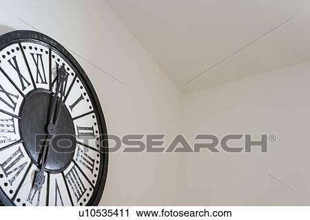 Stock Image - Large wall clock in corner, low angle. Fotosearch