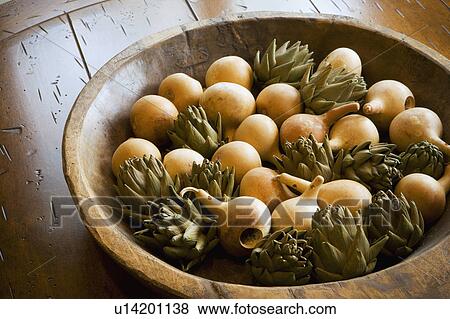 Stock Photo - Detail of wooden bowl filled with wooden pear and artichokes.. Fotosearch