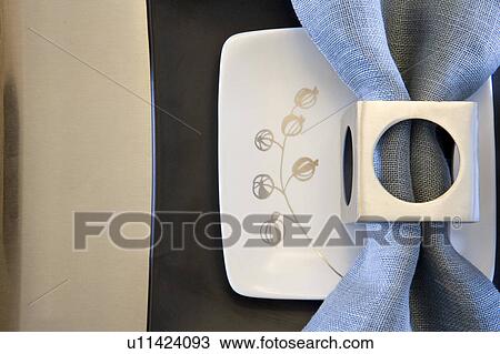 Stock Image - Place setting with plates and napkin with napkin ring (close up). Fotosearch