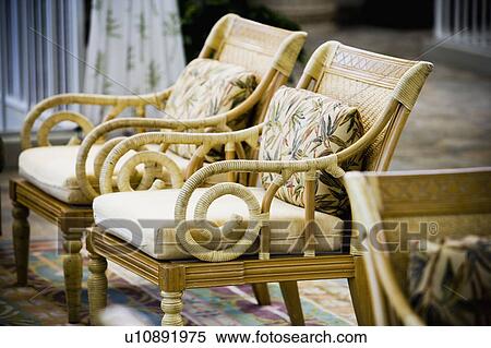 Stock Photography - Two Wood Chairs with White Cushions and Leaf Print Pillows. Fotosearch