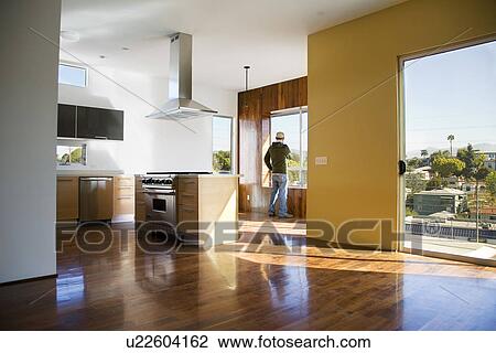 Stock Image - Empty Modern Condomimium with Man at Window. Fotosearch