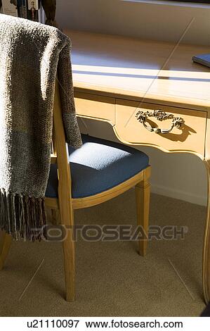 Stock Photo - Chair with blue cushion at wood desk. Fotosearch