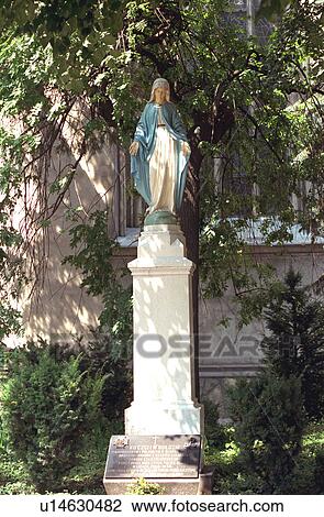 Stock Image - Statue of Mother Mary with head down and hand out praying. Fotosearch