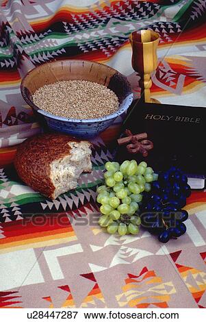 Stock Photo - Wheat bread grapes cross chalice and bible on Navajo blanket. Fotosearch