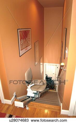 Stock Image - Chair lift in a home. This lift allows the homeowner to go up and down the stairs without assistance.. Fotosearch