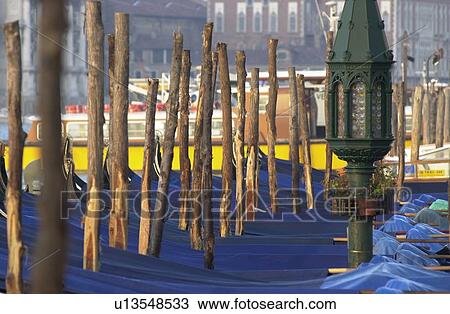 Stock Image - Array of gondolas docked at a canal in Venice, Italy. Fotosearch