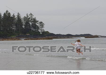 Stock Photo - Girl running through water, Wickaninnish Beach, Vancouver Island, Canada. Fotosearch