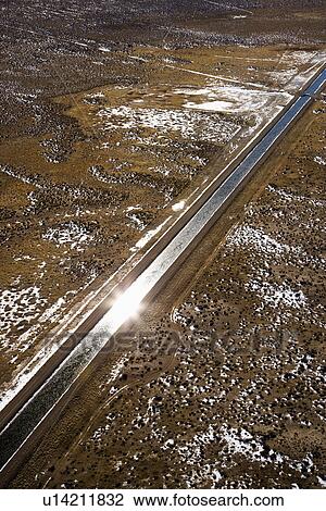 Stock Image - Aerial landscape of water canal running though rural Colorado with sun reflection. Fotosearch