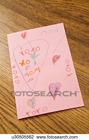 Stock Image - Child drawing with crayons on pink paper. Fotosearch