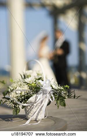 Flower basket with bride and groom blurred in background View Large Photo Image Stock Photo - Flower basket with bride and groom blurred in background. Fotosearch
