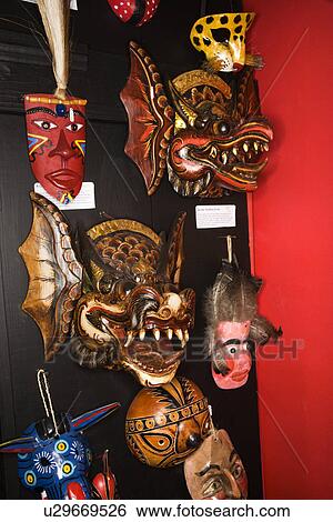 Stock Photograph - Folk art masks hanging in retail store. Fotosearch