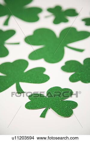Picture - Group of green paper shamrocks on white. Fotosearch