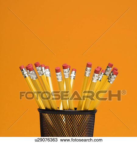 Stock Image - Group of pencils in pencil holder on orange background. Fotosearch