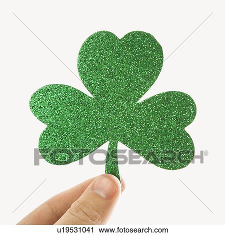 Stock Image - Hand holding a green glitter paper shamrock. Fotosearch