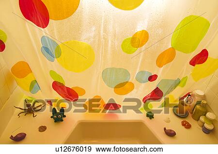 Stock Photo - High angle of polka dotted shower curtain and bathtub toys. Fotosearch
