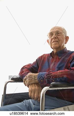 Picture - Man sitting in wheelchair with hands clasped. Fotosearch