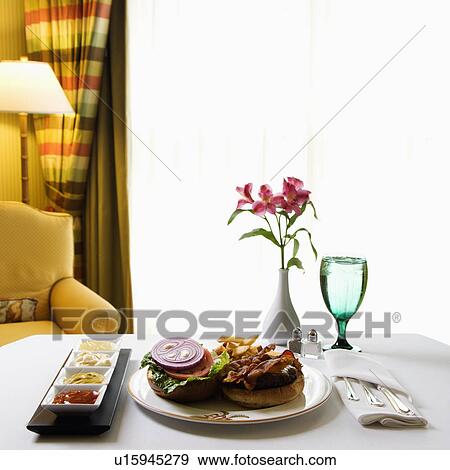 Room service cheeseburger meal with flowers and condiments View Large Photo Image Stock Photo - Room service cheeseburger meal with flowers and condiments. Fotosearch