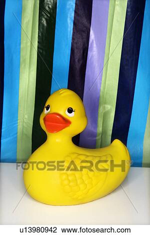 Stock Image - Still life of rubber duck with a striped shower curtain in background. Fotosearch