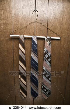 Three retro ties hanging on a wire hanger against wood paneling View Large Photo Image Picture - Three retro ties hanging on a wire hanger against wood paneling. Fotosearch